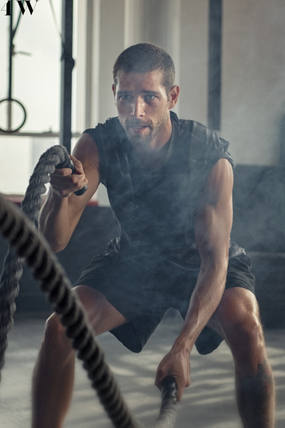 A man working out with heavy battle ropes in a gym